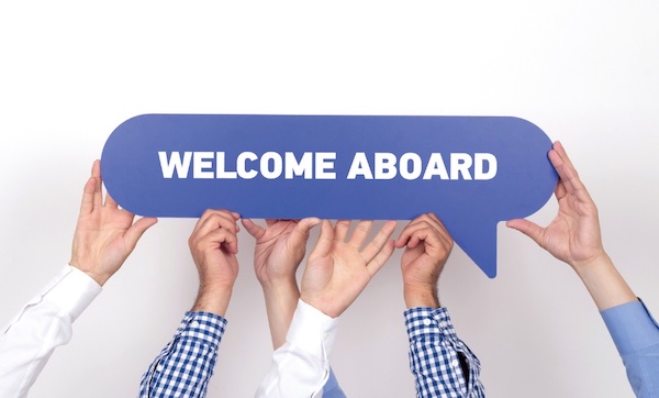 stock image of employees holding up a welcome aboard sign